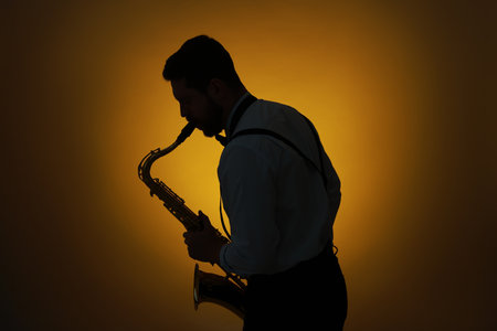 Professional musician playing saxophone on color background, backlitの写真素材