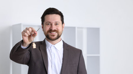 Real estate agent holding key with house shaped keychain indoors, selective focusの写真素材
