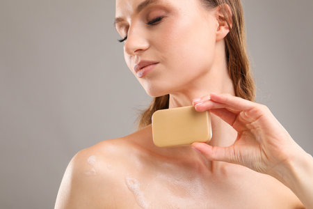 Woman with soap bar on grey background, closeupの写真素材