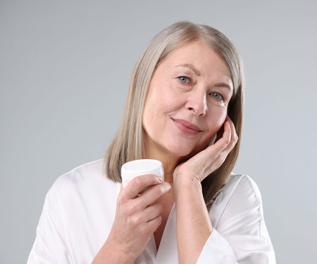 Woman with jar of collagen cream on grey backgroundの写真素材