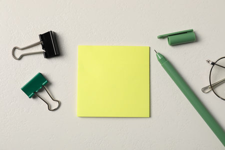 Sticky note, pen and binder clips on white table, flat lay