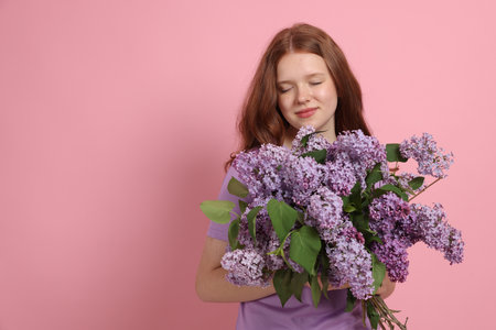 Beautiful teenage girl with bouquet of lilac flowers on pink background. Space for textの写真素材