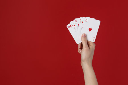 Woman with playing cards against red background, closeup. Space for textの写真素材