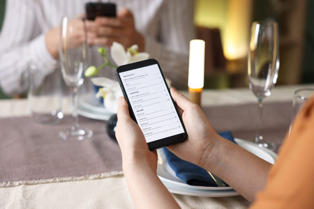 Couple choosing dishes from digital menu at restaurant, closeup