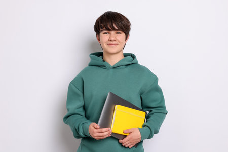 Teenage boy with laptop and notebook on white backgroundの写真素材