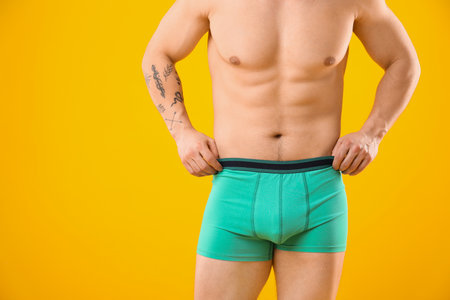 Young man in stylish turquoise underwear on orange background, closeup. Space for textの写真素材