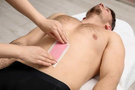Young man undergoing wax epilation in salonの写真素材