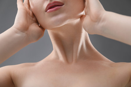 Woman with beautiful collarbones and neck on grey background, closeup