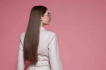 Woman in stylish outfit on pink background. Space for textの写真素材