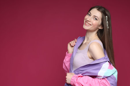 Fashionable portrait of beautiful woman in stylish outfit on crimson background. Space for textの写真素材