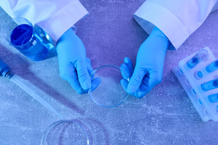 Scientist with Petri dish at table, top view