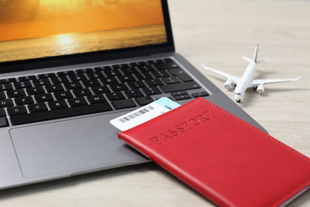 Passport, flight ticket, plane model and laptop on wooden table, closeupの写真素材