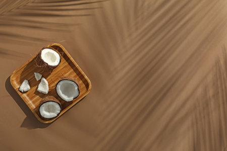 Fresh coconuts and shadow cast by tropical palm on beige background, top view. Space for textの写真素材