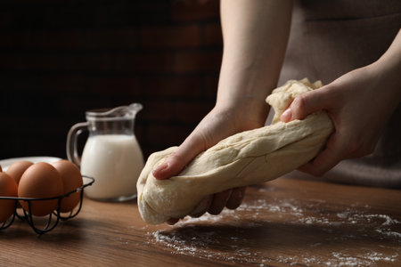 Woman kneading raw dough at wooden table, closeupの写真素材