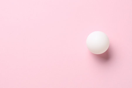 Ping pong ball on pink background, top view. Space for text