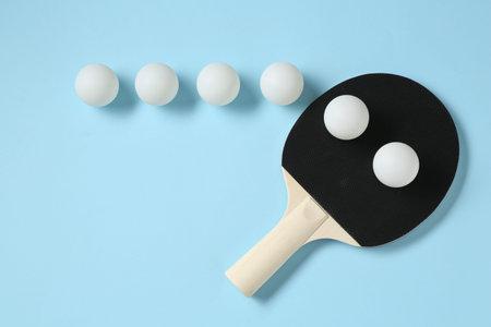 Ping pong racket and balls on light blue background, flat lay