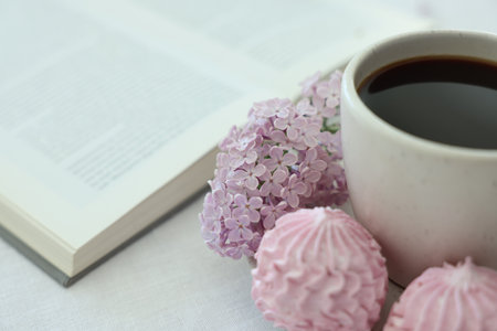 Coffee with dessert, lilac flowers and book on white table, closeupの写真素材