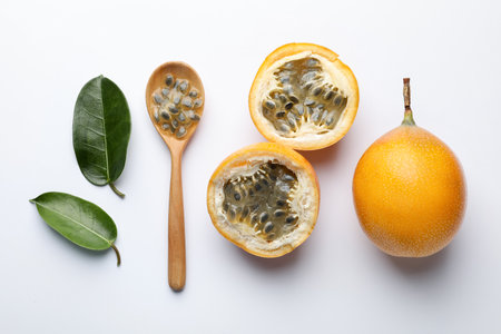 Ripe passion fruits, seeds and green leaves on white background, flat layの写真素材