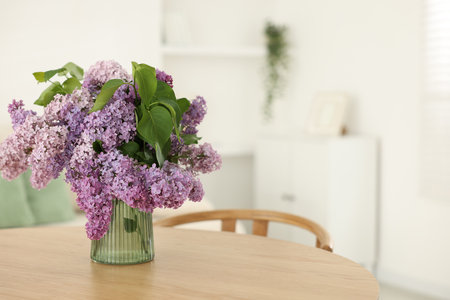 Beautiful lilac flowers in vase on wooden table indoors, space for textの写真素材