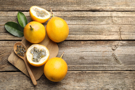 Ripe passion fruits, seeds and leaves on wooden table, flat lay. Space for textの写真素材