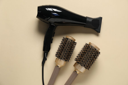 Round brushes and dryer on beige background, flat layの写真素材