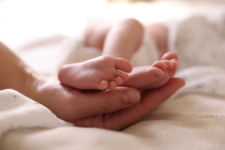 Mother with her little baby on bed indoors, closeup