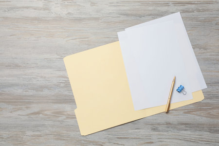 Paper file folder with blank sheets, pen and binder clip on wooden table, top view. Space for text