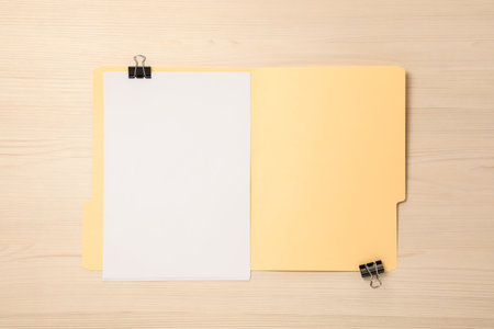 Paper file folder with blank sheets and binder clips on wooden table, top viewの写真素材