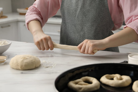 Woman shaping pretzels at table in kitchen, closeup