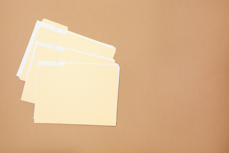 File folders with papers on light brown background, flat lay. Space for textの写真素材