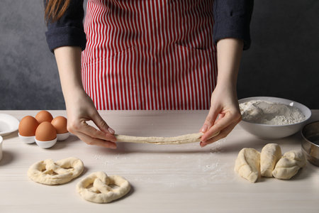 Woman making pretzel at white wooden table, closeupの写真素材