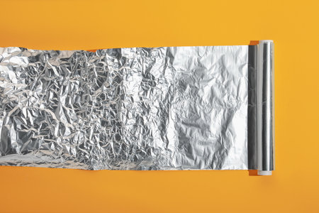 Roll of aluminum foil on orange background, top viewの写真素材