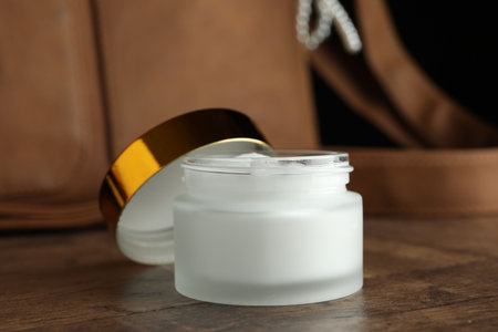 Jar of moisturizing body cream and leather bag on wooden table, closeupの写真素材