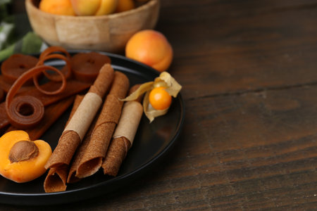 Tasty fruit leather, physalis and apricots on wooden table, closeup. Space for textの写真素材
