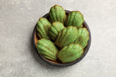 Tasty matcha madeleine cakes on light table, top view