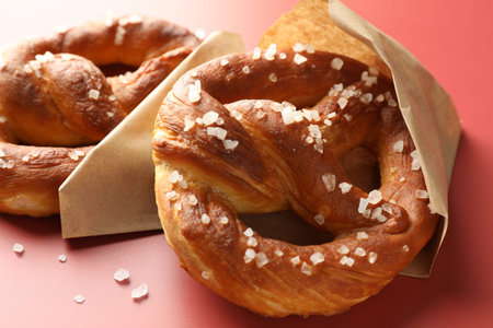 Tasty pretzels with salt on red background, closeup