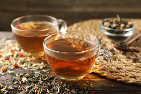 Refreshing herbal tea and dry leaves on wooden table, closeupの写真素材
