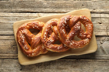 Tasty pretzels with salt on wooden table, top view