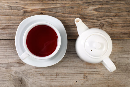 Delicious hibiscus tea in cup and teapot on wooden table, flat layの写真素材
