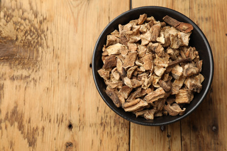 Pieces of dry chicory roots in bowl on wooden table, top view. Space for textの写真素材