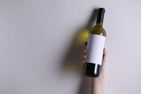 Woman with bottle of wine on white background, closeup. Space for textの写真素材