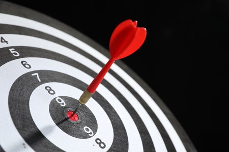 Targeting. Dart board with arrow on black background, closeupの写真素材