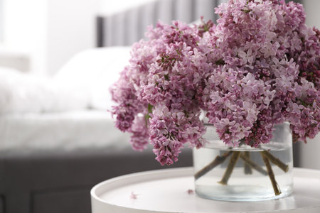 Beautiful lilac flowers in glass vase on table indoors, closeup. Space for textの写真素材