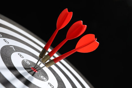 Targeting. Dart board with arrows on black background, closeup