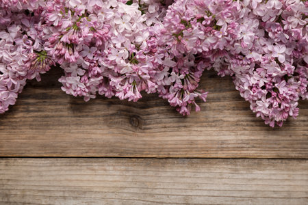 Beautiful lilac flowers on wooden table, flat lay. Space for textの写真素材