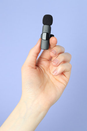 Woman holding lavalier microphone on light blue background, closeupの写真素材