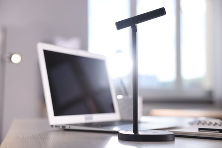 Microphone and laptop on white wooden desk in officeの写真素材