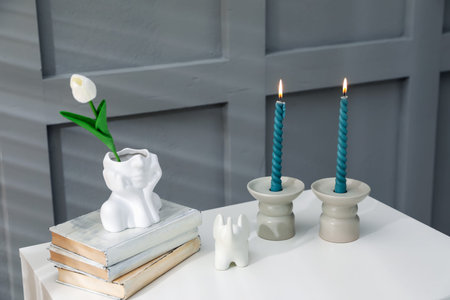 Candlesticks with burning candles on table near grey wallの写真素材