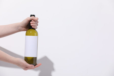 Woman with bottle of wine on white background, closeup. Space for text