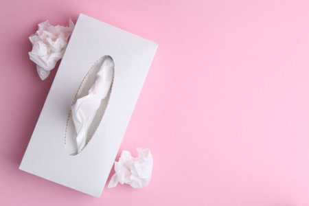 Box with paper handkerchiefs and crumpled tissues on pink background, flat lay. Space for textの写真素材